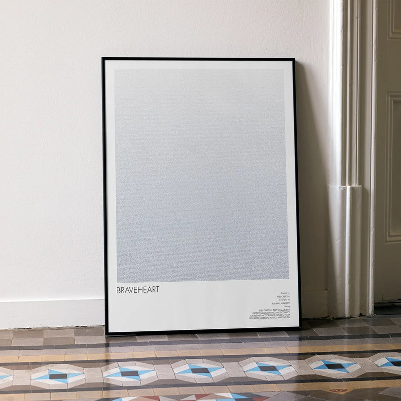 A framed Braveheart movie script poster leaning against a wall in a minimalist interior.