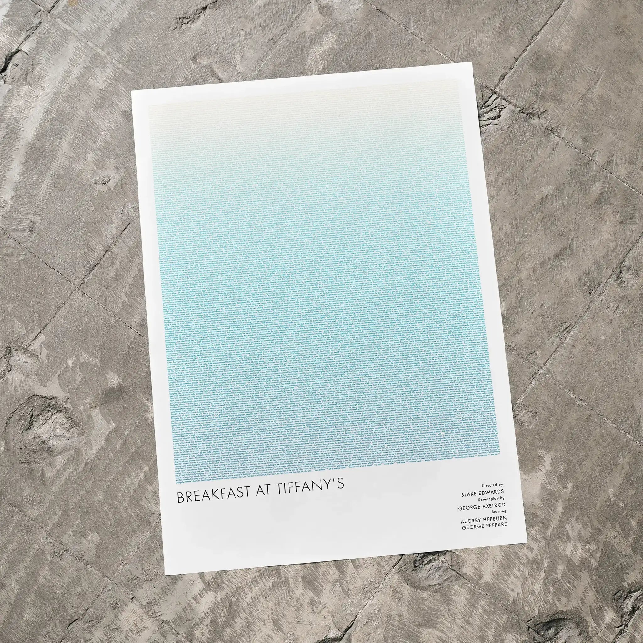 A Breakfast at Tiffany's movie script poster laid flat on a textured floor surface.