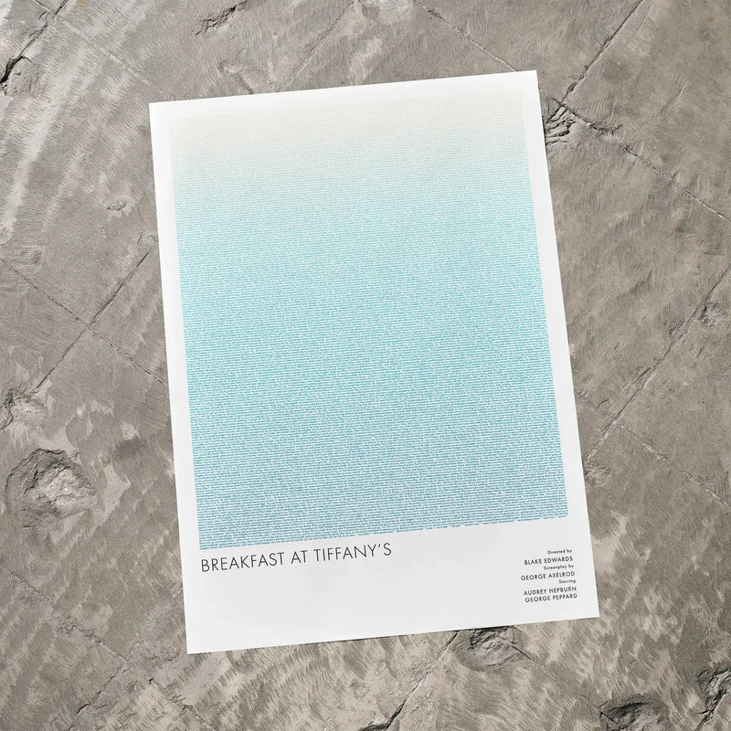 A Breakfast at Tiffany's movie script poster laid flat on a textured floor surface.