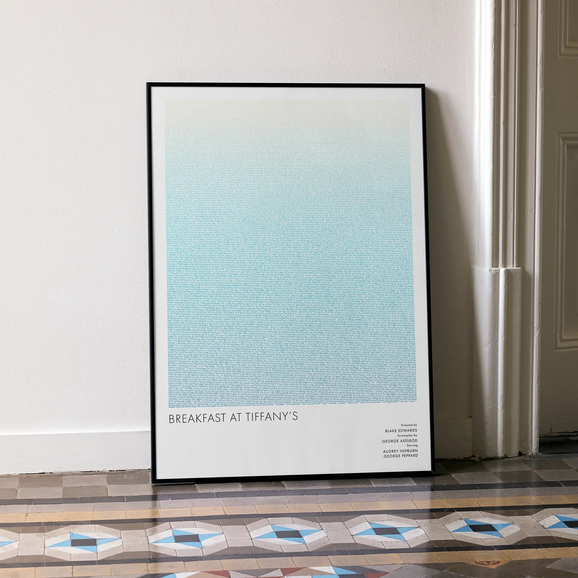 A framed Breakfast at Tiffany's movie script poster leaning against a wall in a minimalist interior.