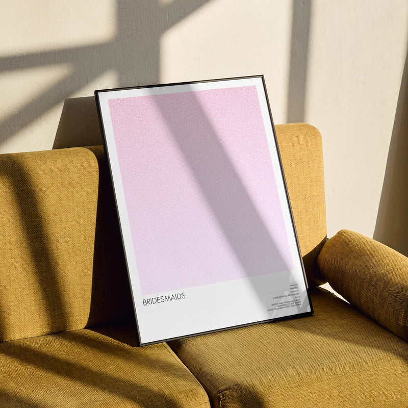 A framed Bridesmaids movie script poster styled in a clean interior setting.