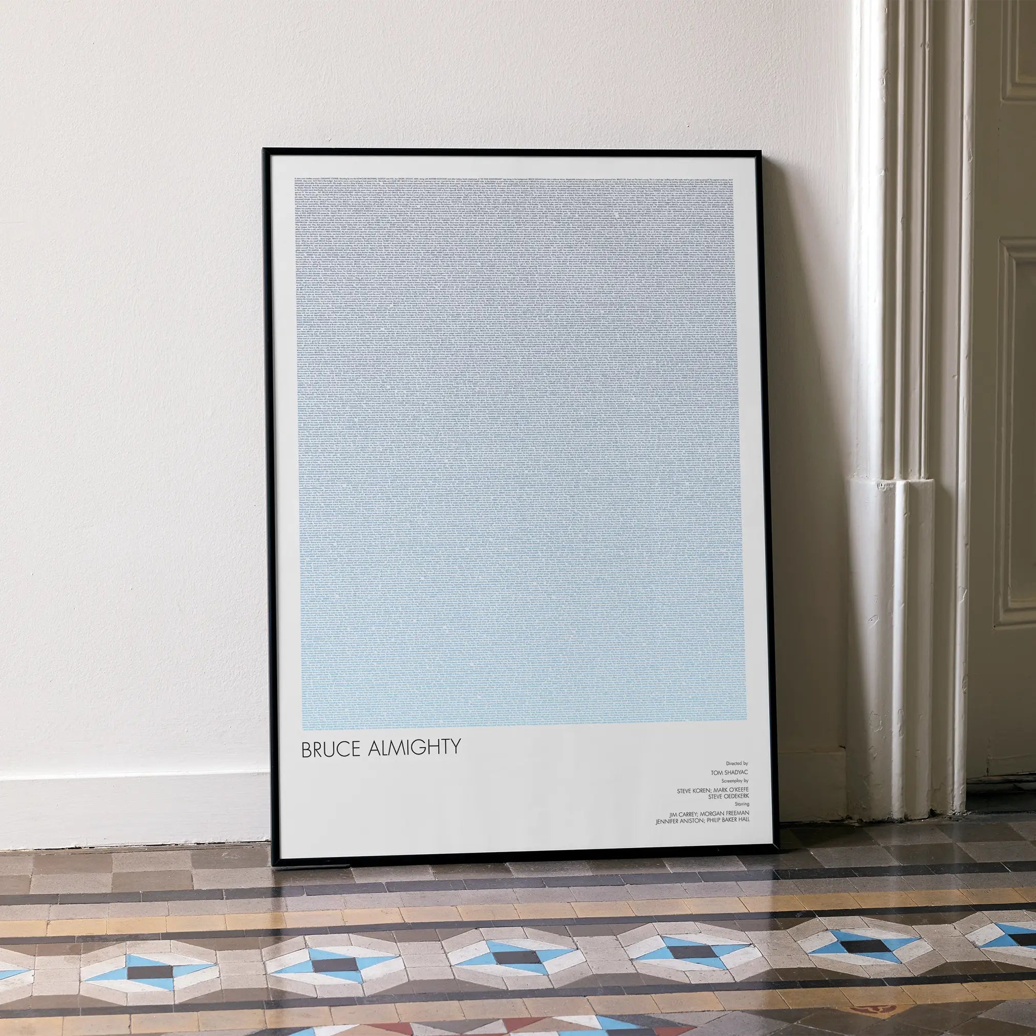 A framed Bruce Almighty movie script poster leaning against a wall in a minimalist interior.