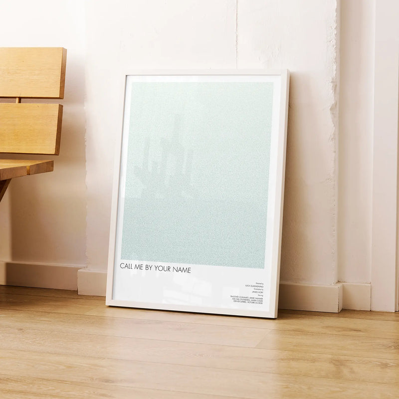 A framed Call Me by Your Name movie script poster leaning against a wall in a modern interior.