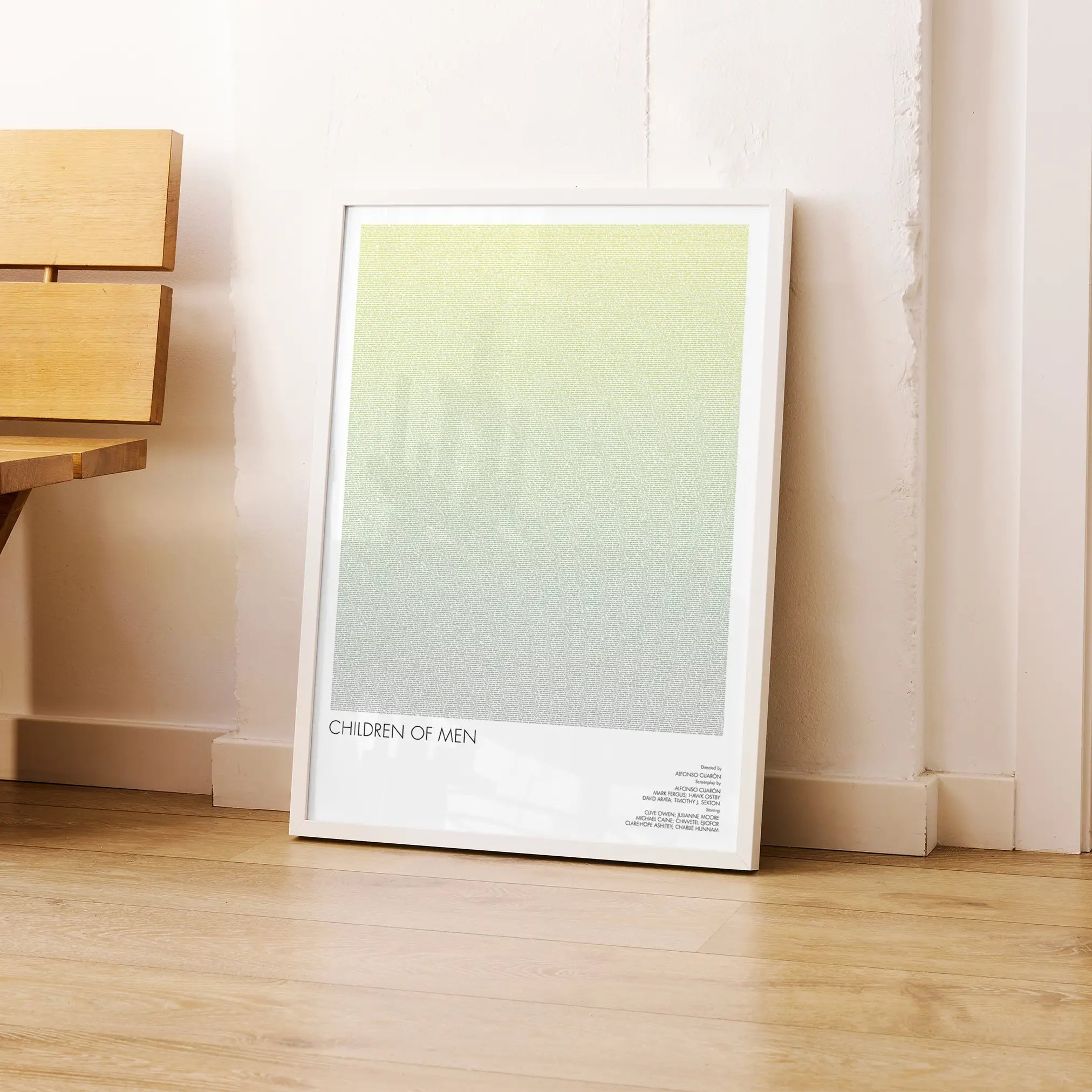 A framed Children of Men movie script poster leaning against a wall in a modern interior.