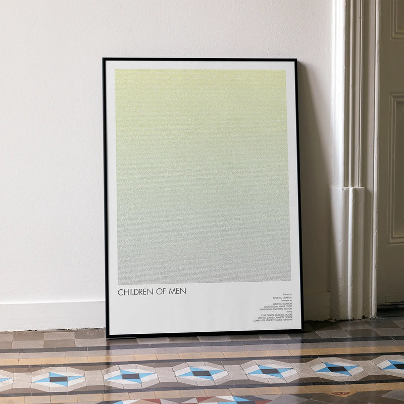 A framed Children of Men movie script poster leaning against a wall in a minimalist interior.
