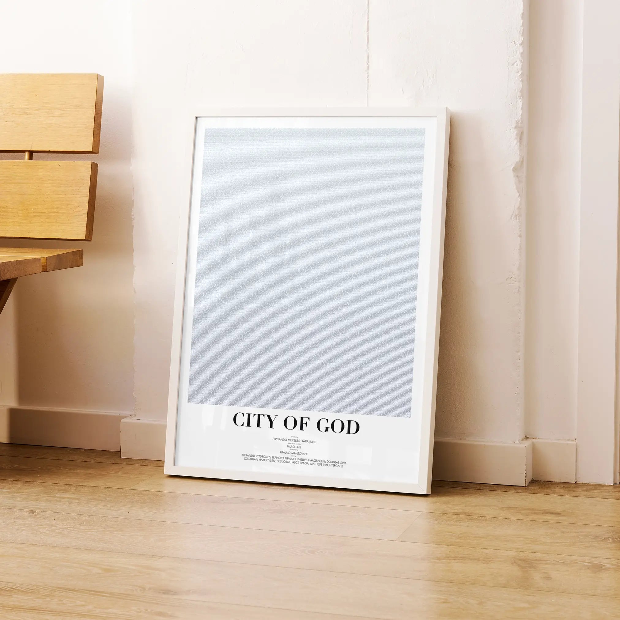 A framed City of God movie script poster leaning against a wall in a modern interior.