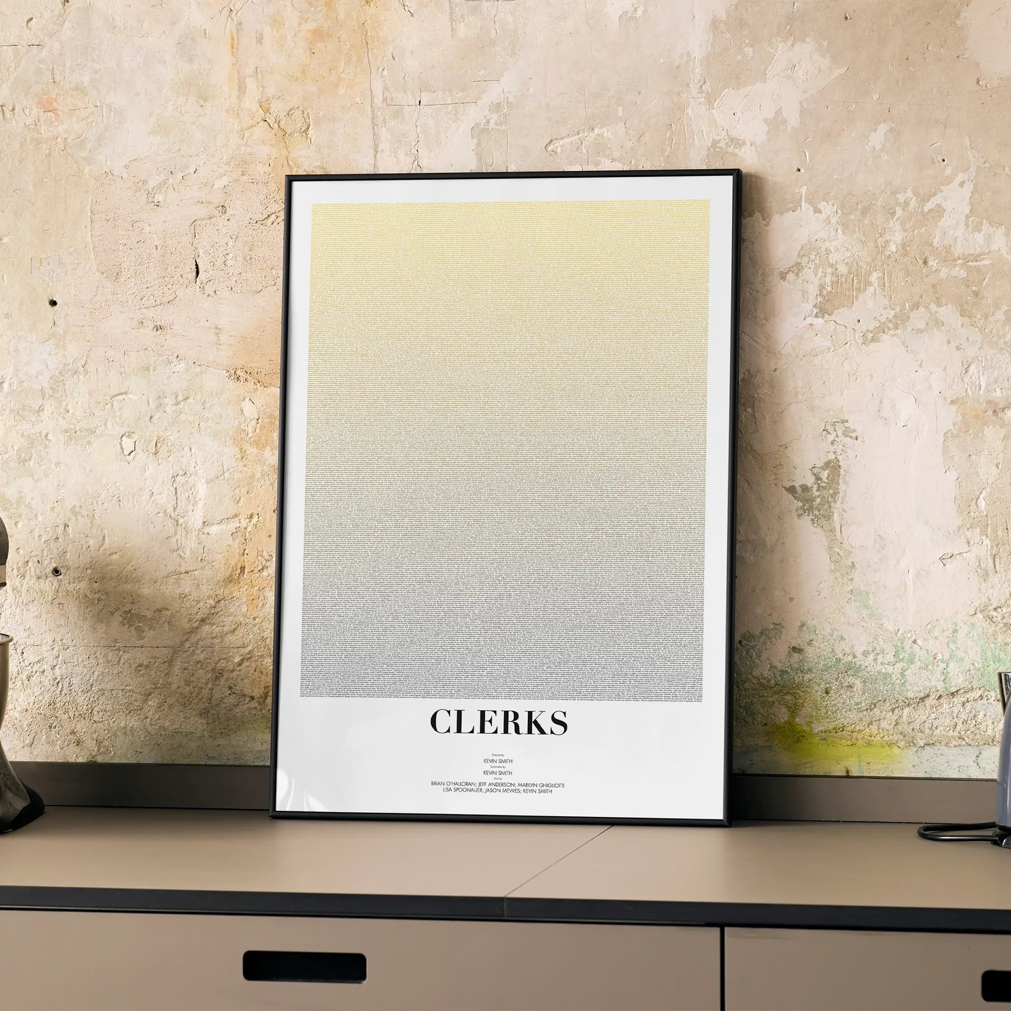 A framed Clerks movie script poster displayed on a cabinet in a minimalist interior.