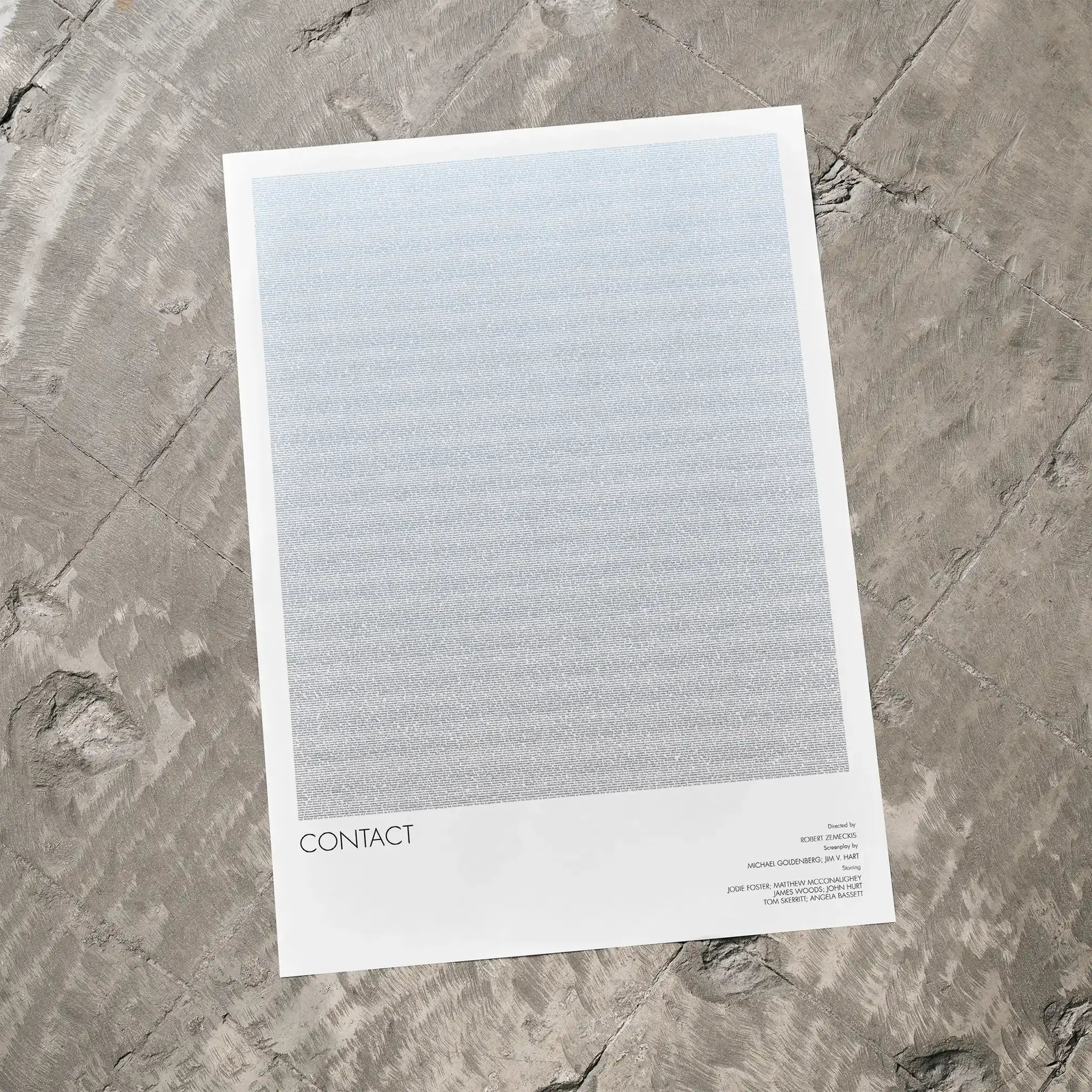 A Contact movie script poster laid flat on a textured floor surface.
