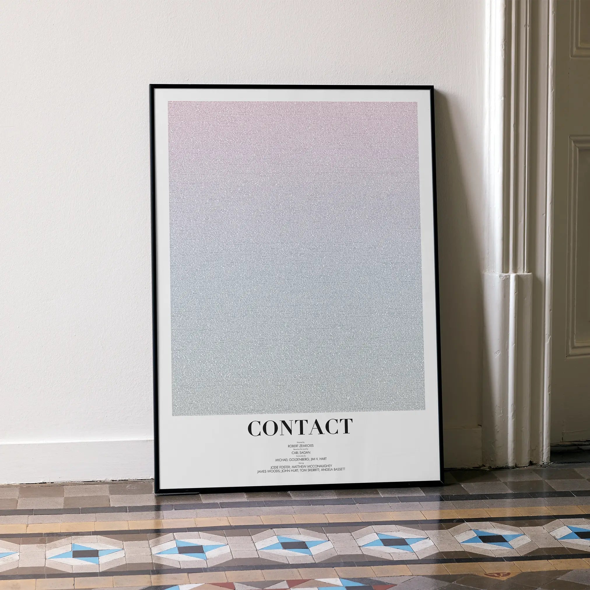 A framed Contact movie script poster leaning against a wall in a minimalist interior.