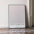 A framed Crazy, Stupid, Love. movie script poster leaning against a wall in a minimalist interior.