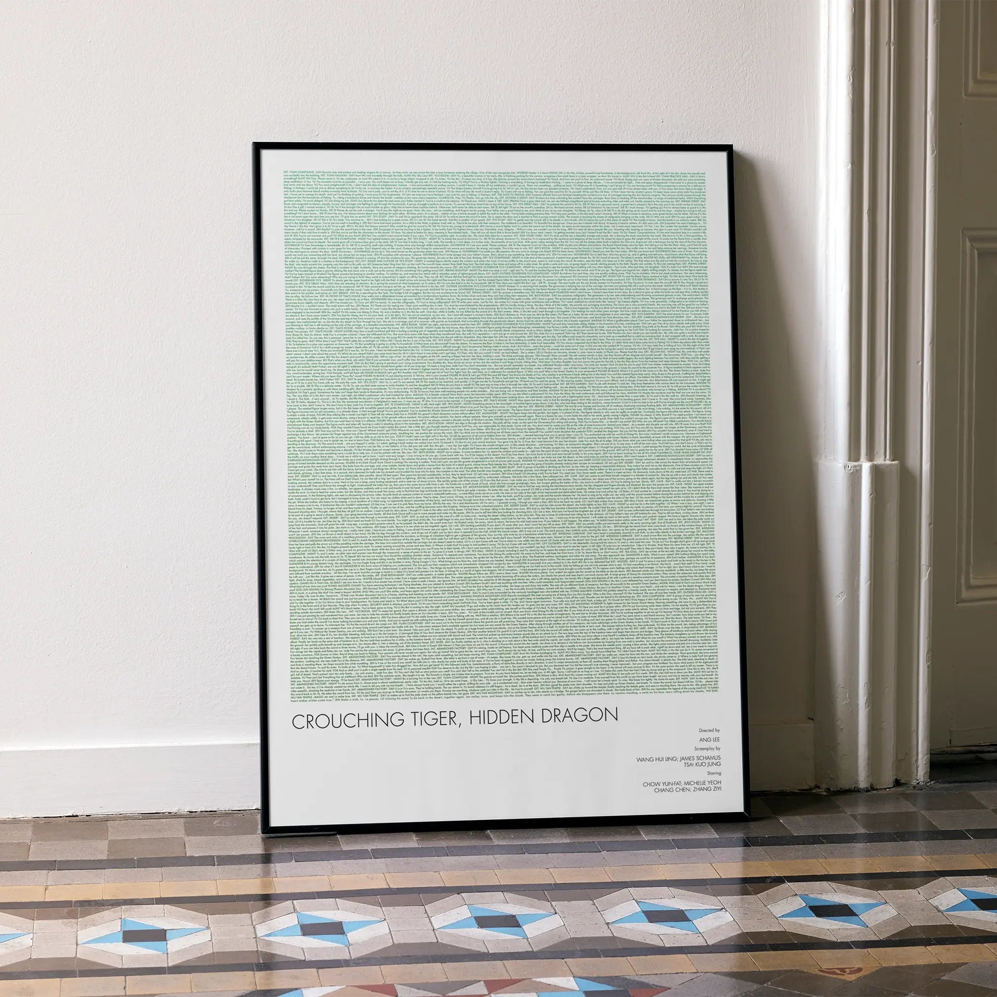 A framed Crouching Tiger, Hidden Dragon movie script poster leaning against a wall in a minimalist interior.