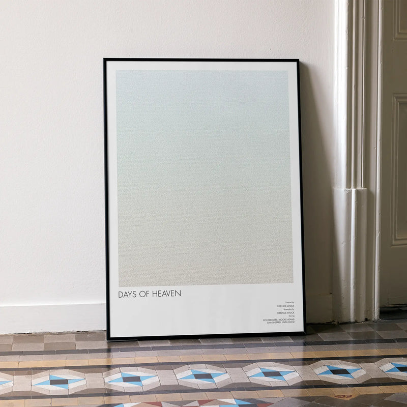 A framed Days of Heaven movie script poster leaning against a wall in a minimalist interior.