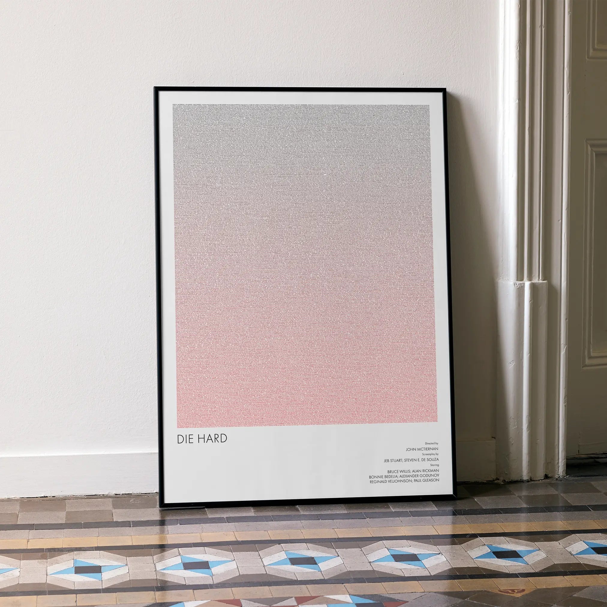 A framed Die Hard movie script poster leaning against a wall in a minimalist interior.