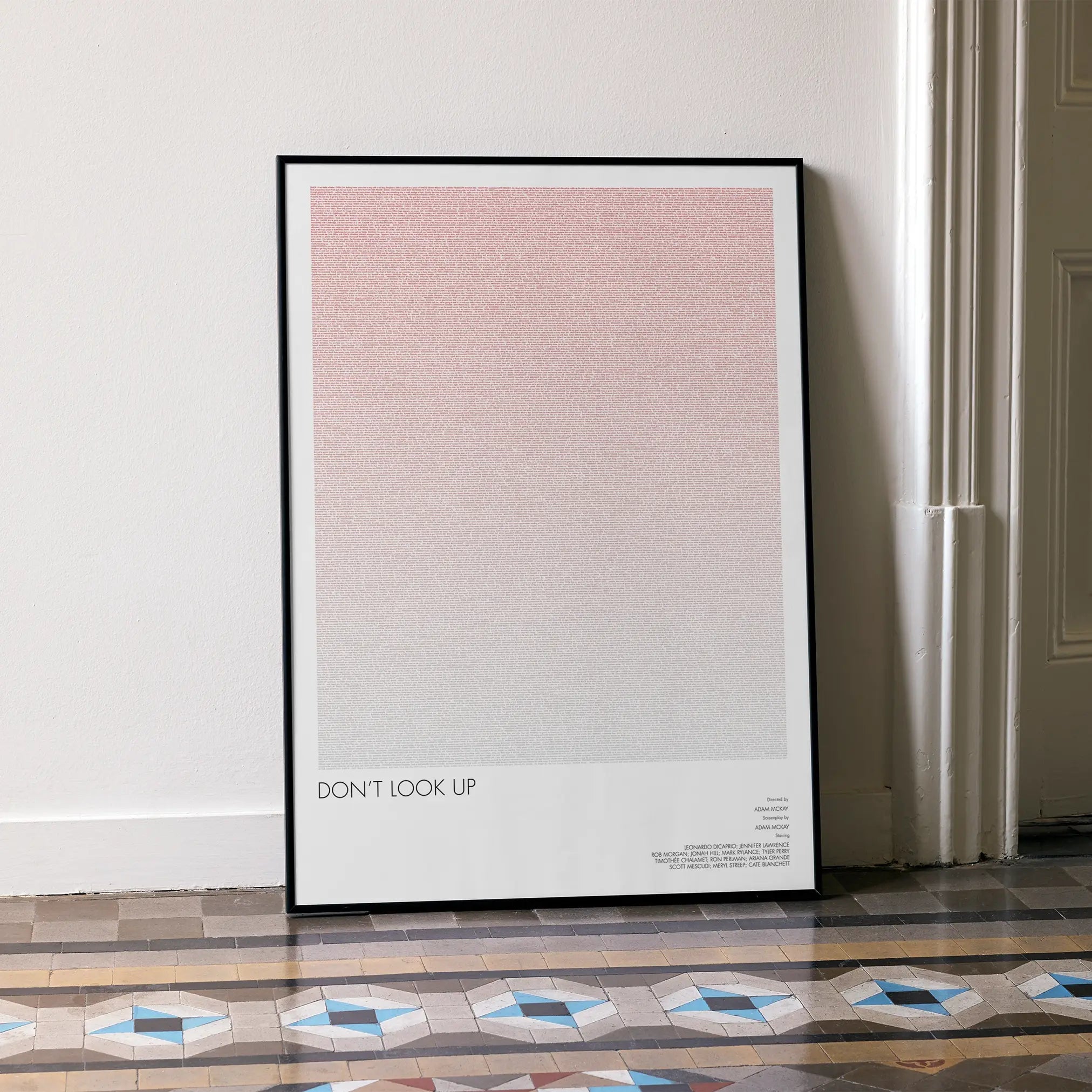 A framed Don't Look Up movie script poster leaning against a wall in a minimalist interior.