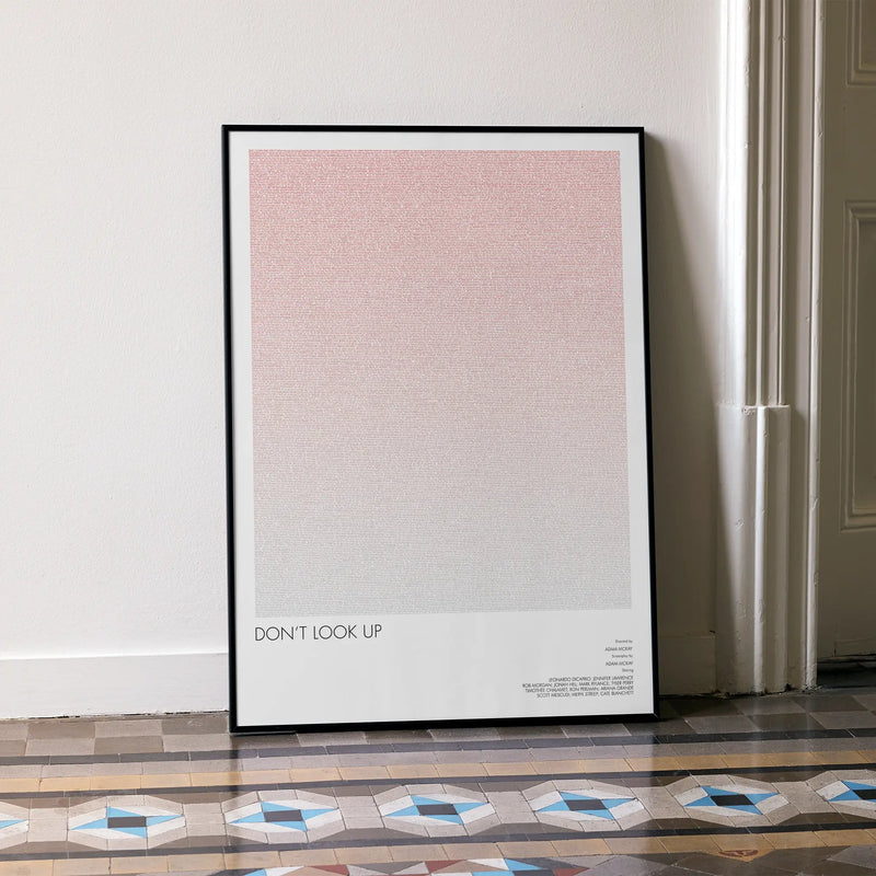 A framed Don't Look Up movie script poster leaning against a wall in a minimalist interior.