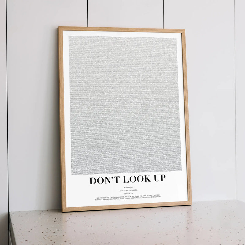 A framed Don't Look Up movie script poster styled within a calm interior space.