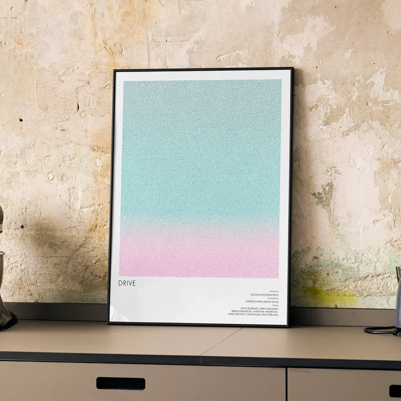 A framed Drive movie script poster displayed on a cabinet in a minimalist interior.