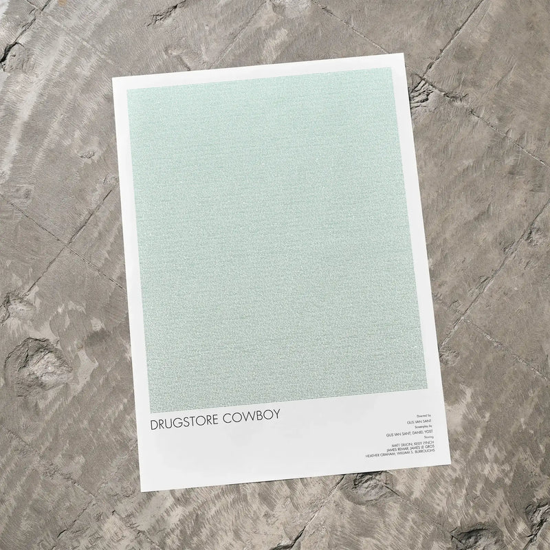 A Drugstore Cowboy movie script poster laid flat on a textured floor surface.
