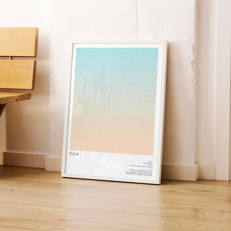A framed Dune movie script poster leaning against a wall in a modern interior.