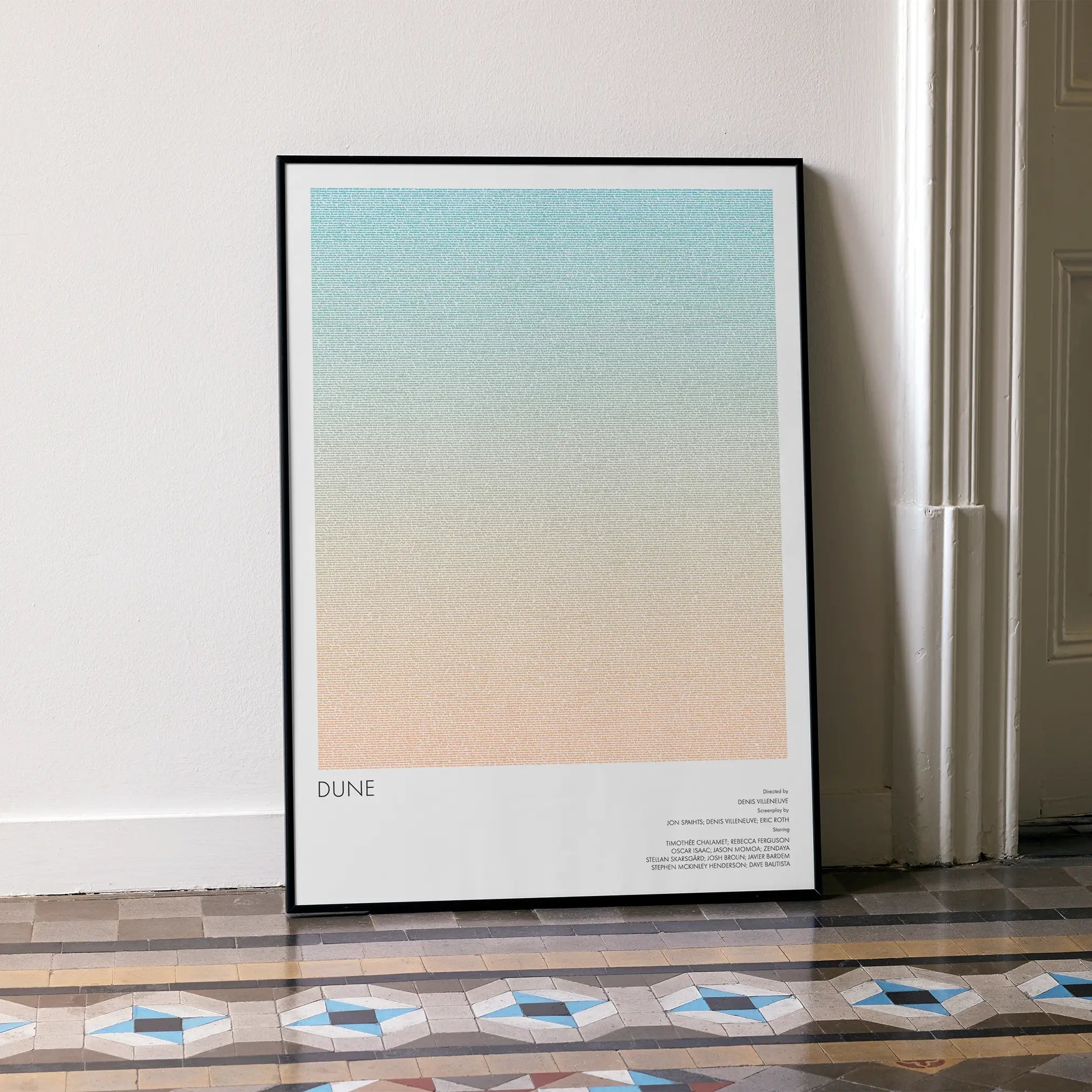 A framed Dune movie script poster leaning against a wall in a minimalist interior.