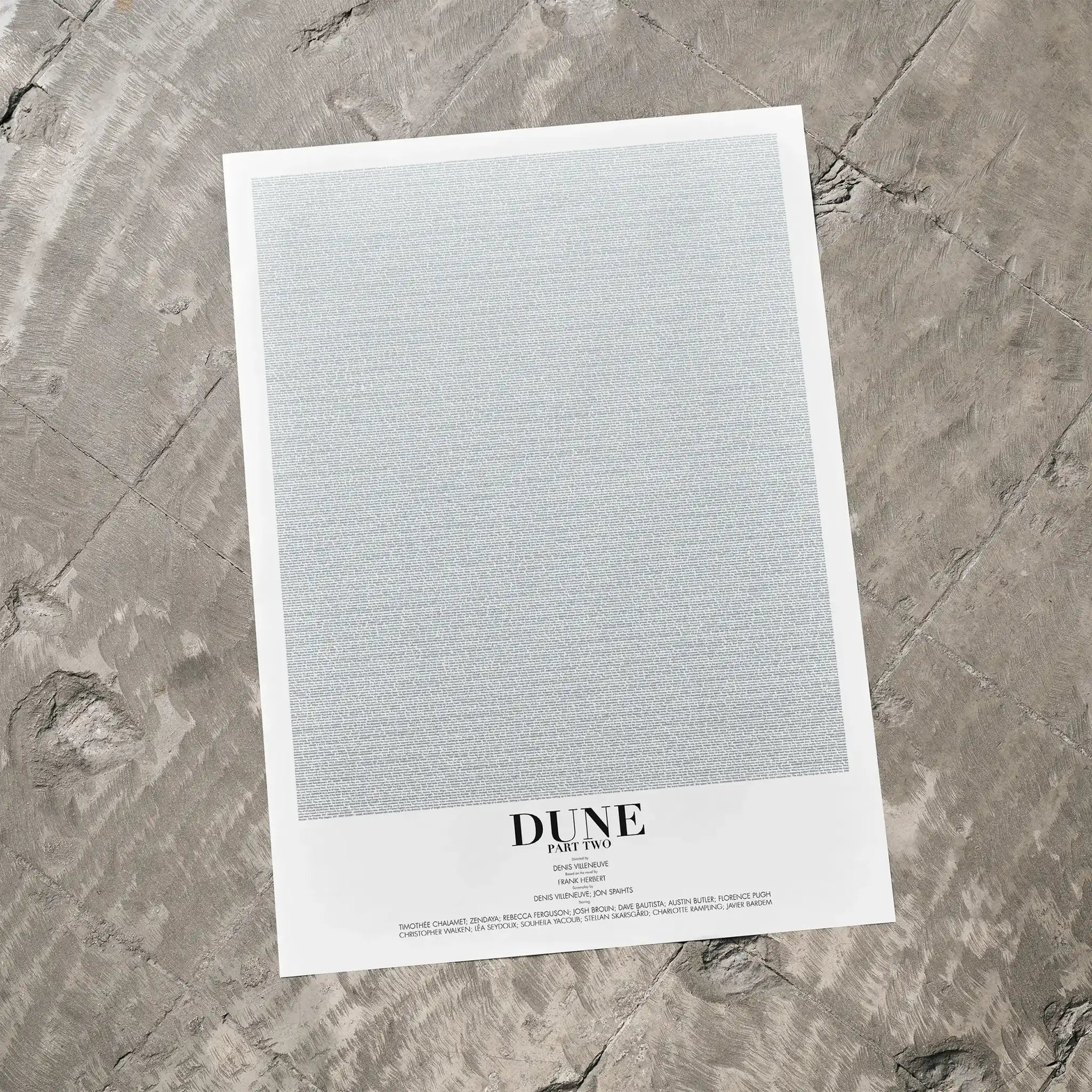 A Dune: Part Two movie script poster laid flat on a textured floor surface.