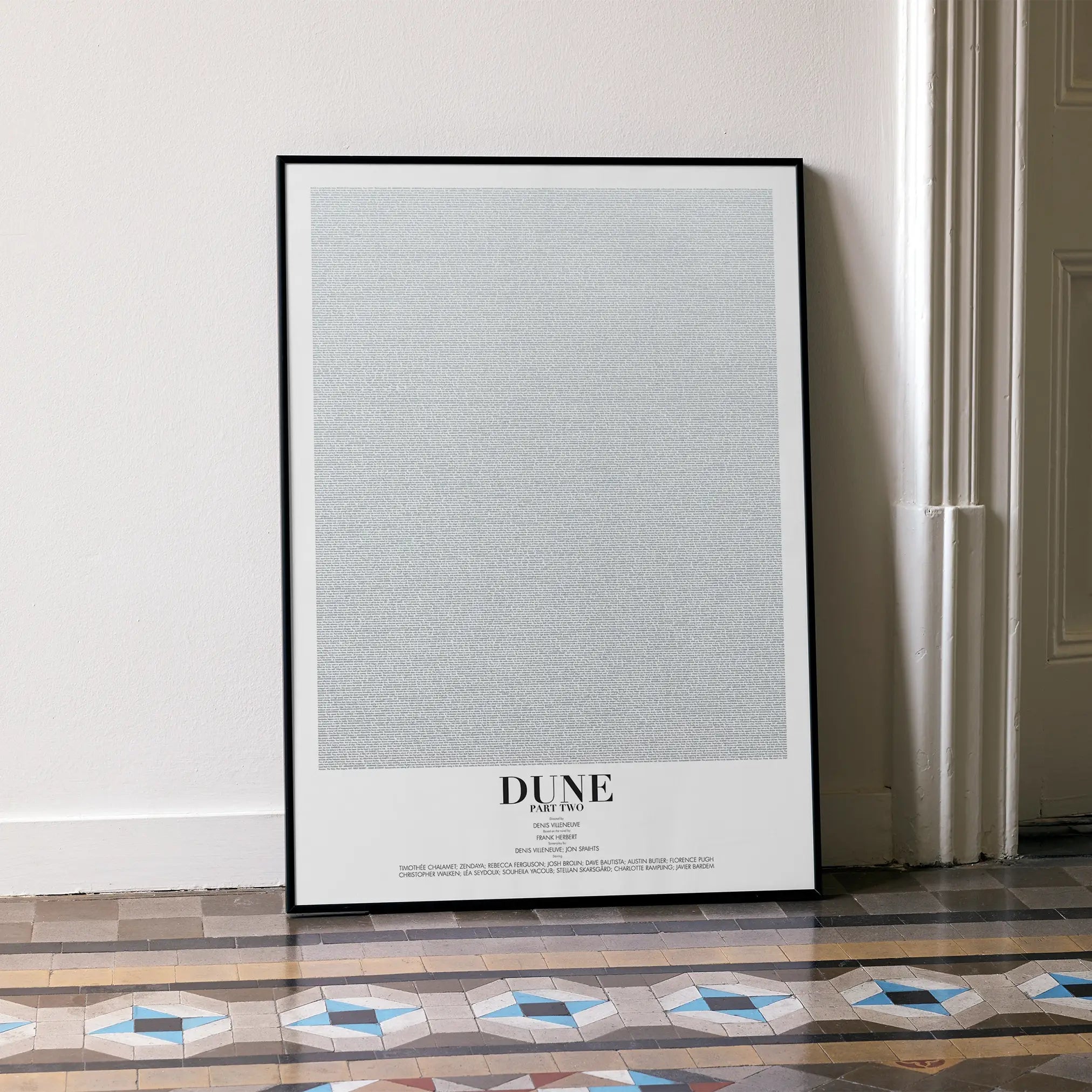 A framed Dune: Part Two movie script poster leaning against a wall in a minimalist interior.