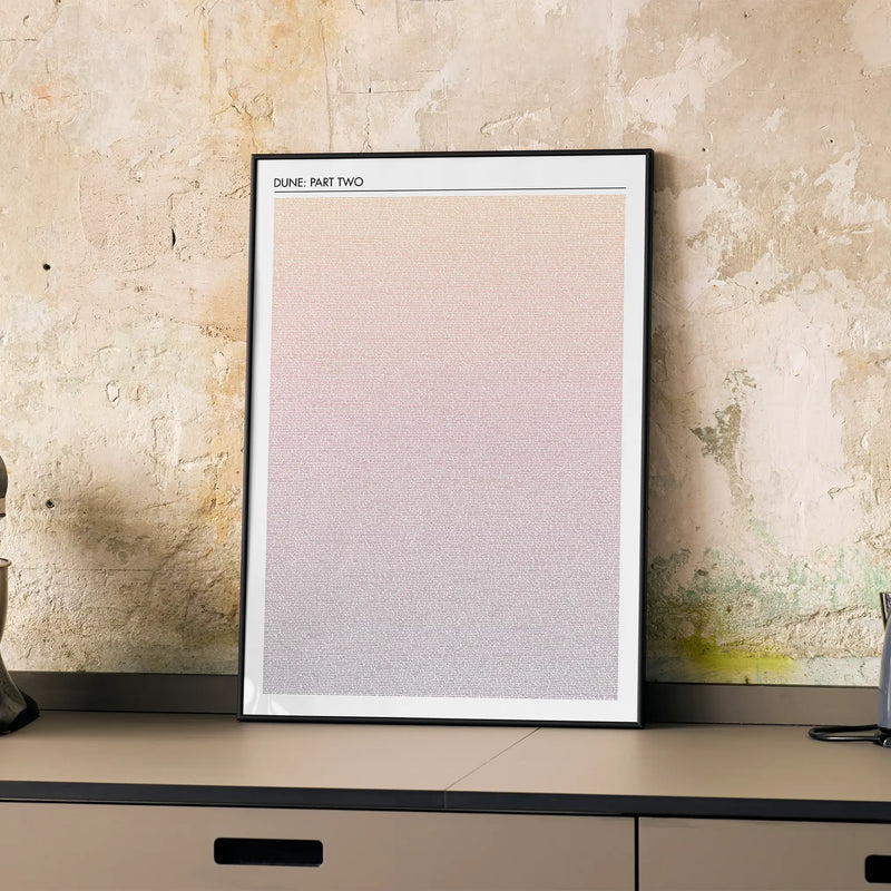 A framed Dune: Part Two movie script poster displayed on a cabinet in a minimalist interior.