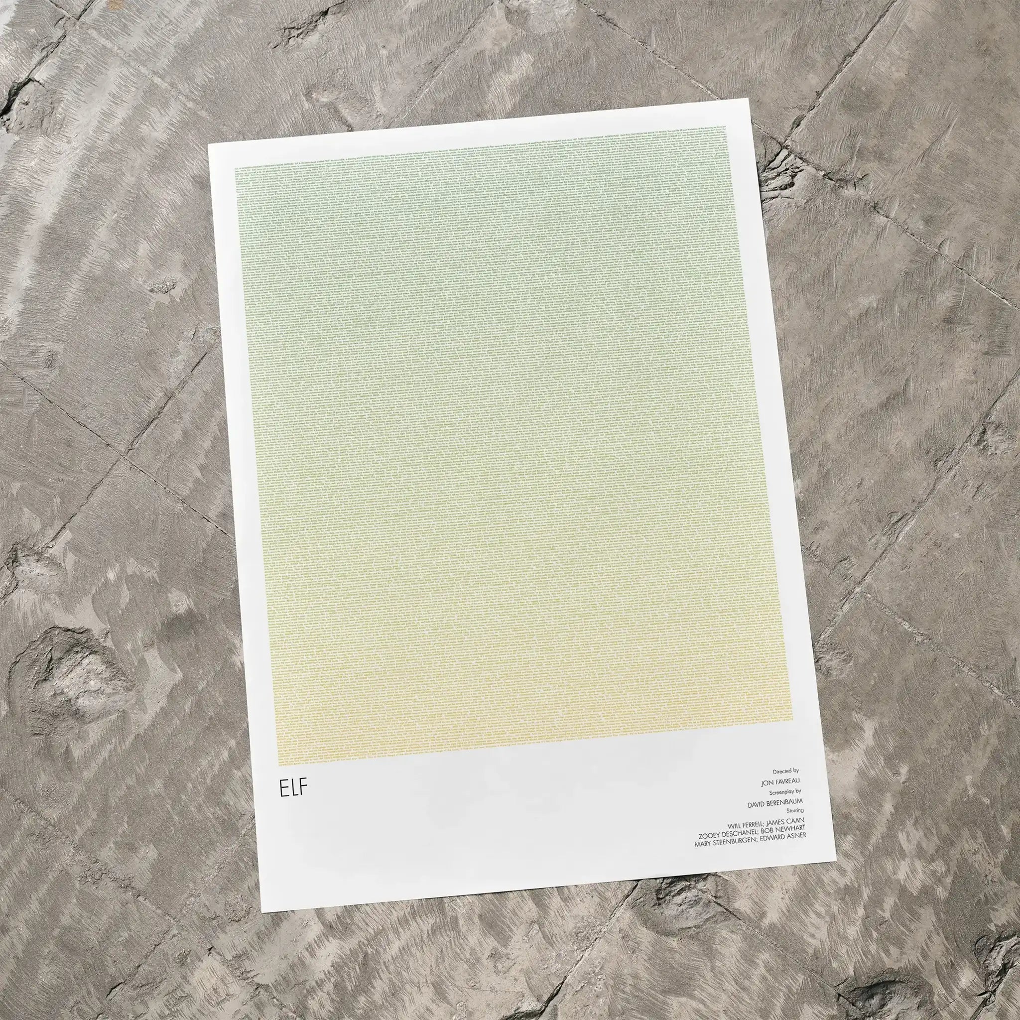 A Elf movie script poster laid flat on a textured floor surface.