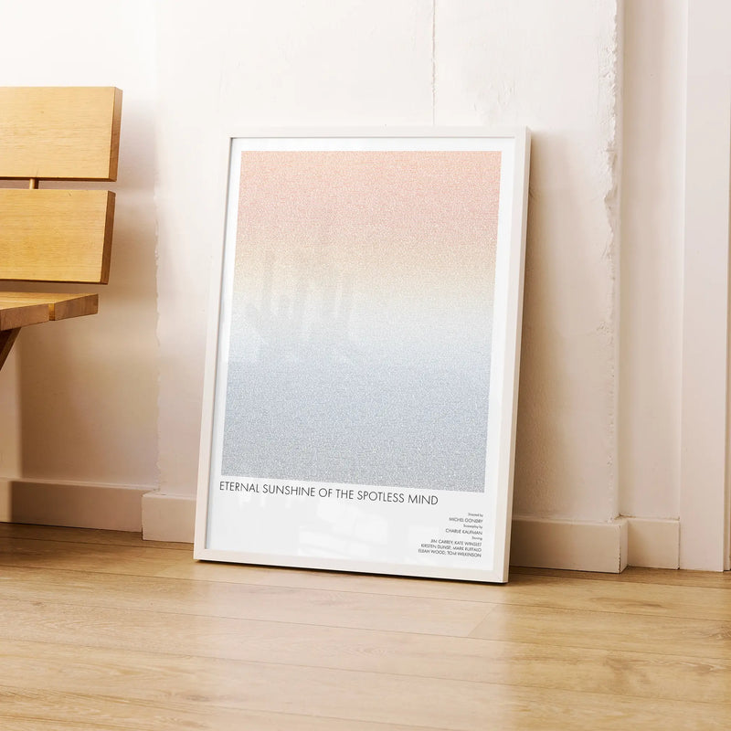 A framed Eternal Sunshine of the Spotless Mind movie script poster leaning against a wall in a modern interior.
