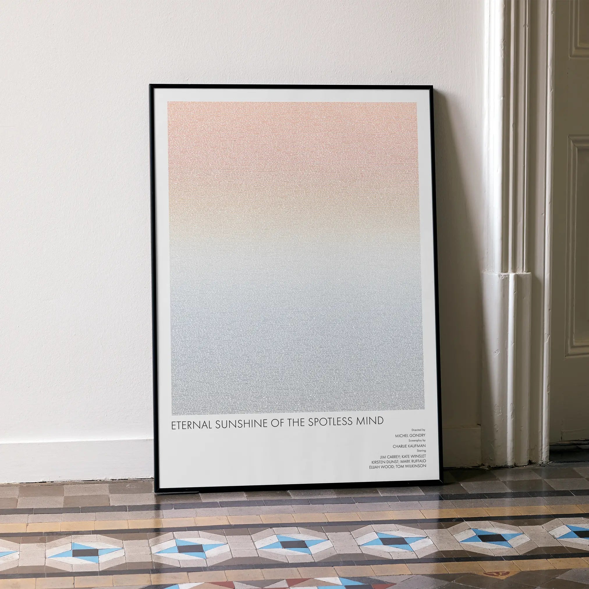 A framed Eternal Sunshine of the Spotless Mind movie script poster leaning against a wall in a minimalist interior.