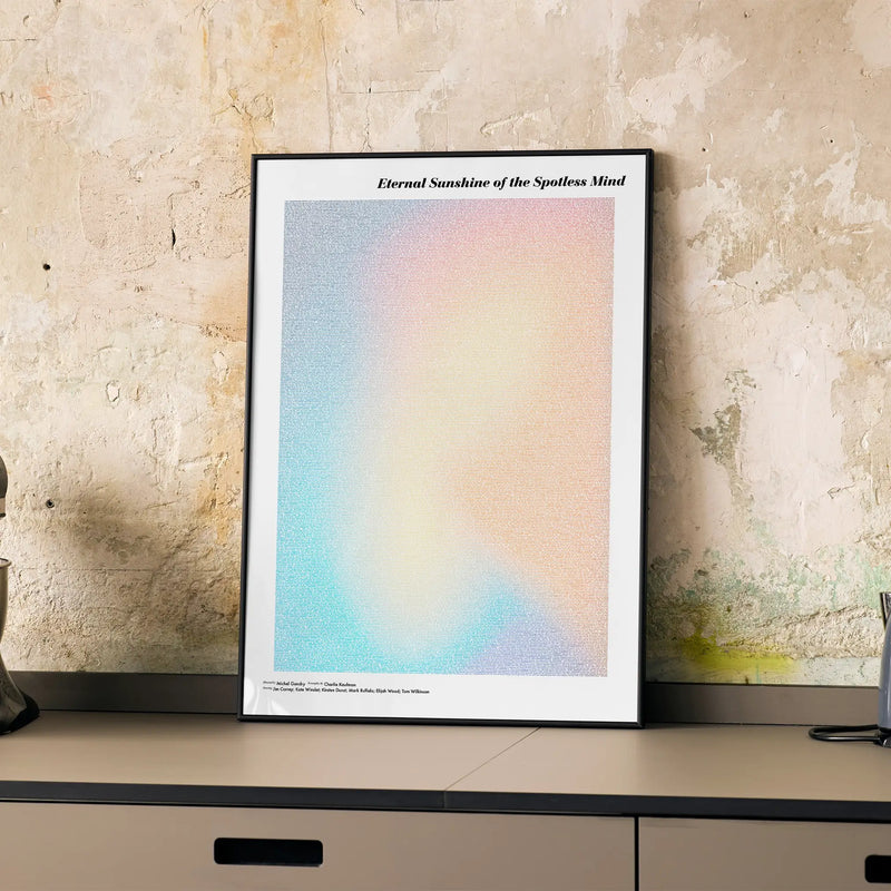 A framed Eternal Sunshine of the Spotless Mind movie script poster displayed on a cabinet in a minimalist interior.