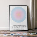Framed Eternal Sunshine of the Spotless Mind movie poster with a colorful aura design and text in a room with a patterned floor.