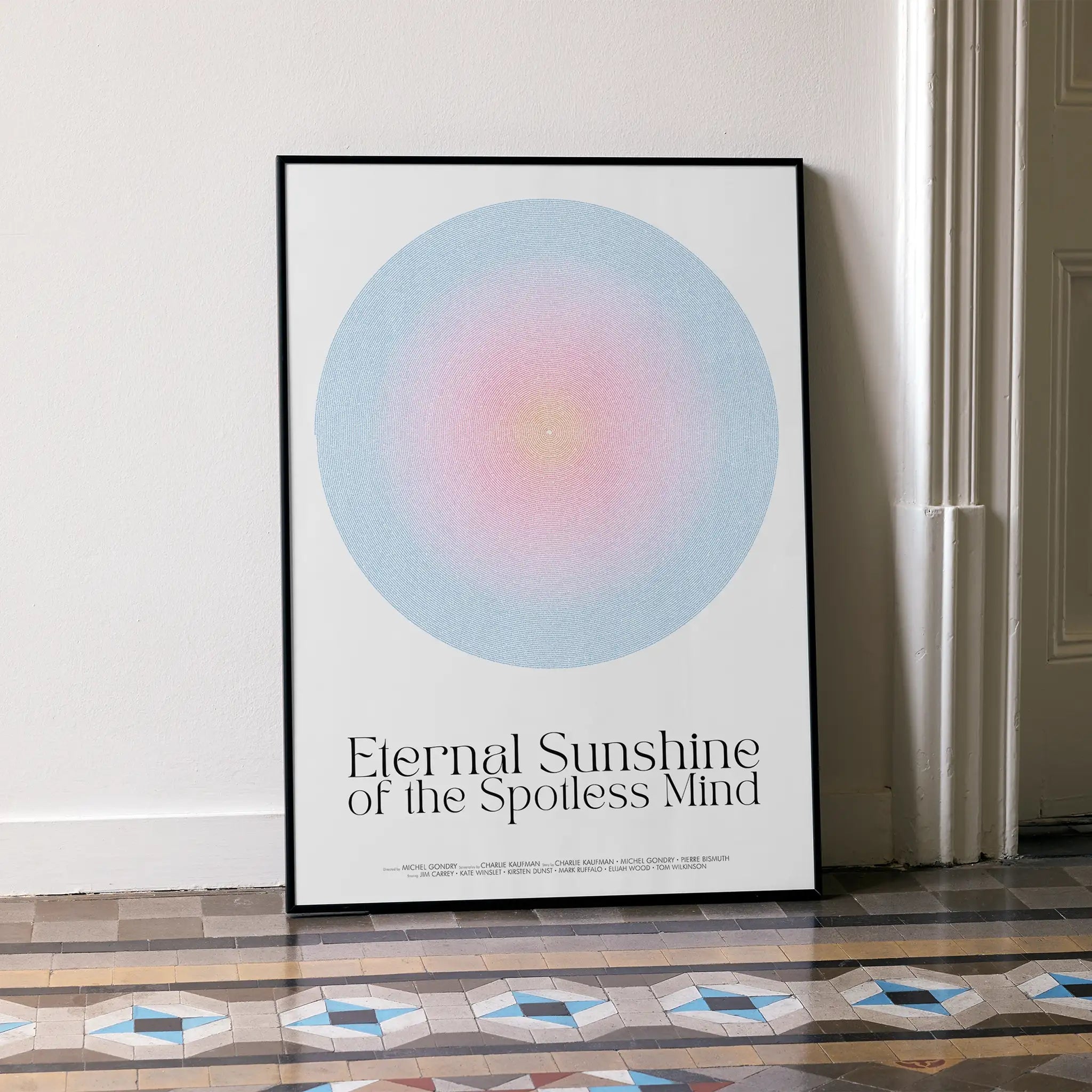 Framed Eternal Sunshine of the Spotless Mind movie poster with a colorful aura design and text in a room with a patterned floor.