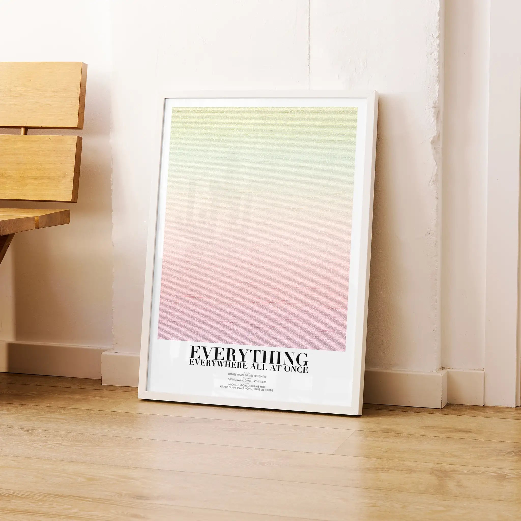 Framed "Everything Everywhere  All At Once" poster with gradient design and text on a wooden floor.
