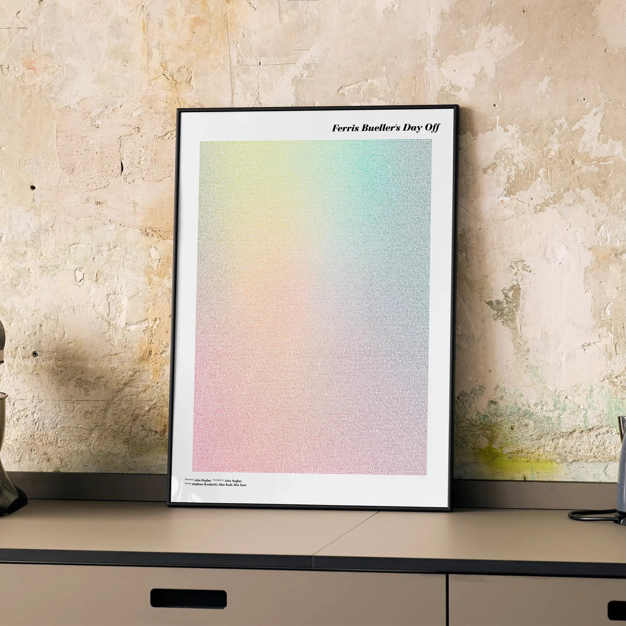 A framed Ferris Bueller’s Day Off movie script poster displayed on a cabinet in a minimalist interior.