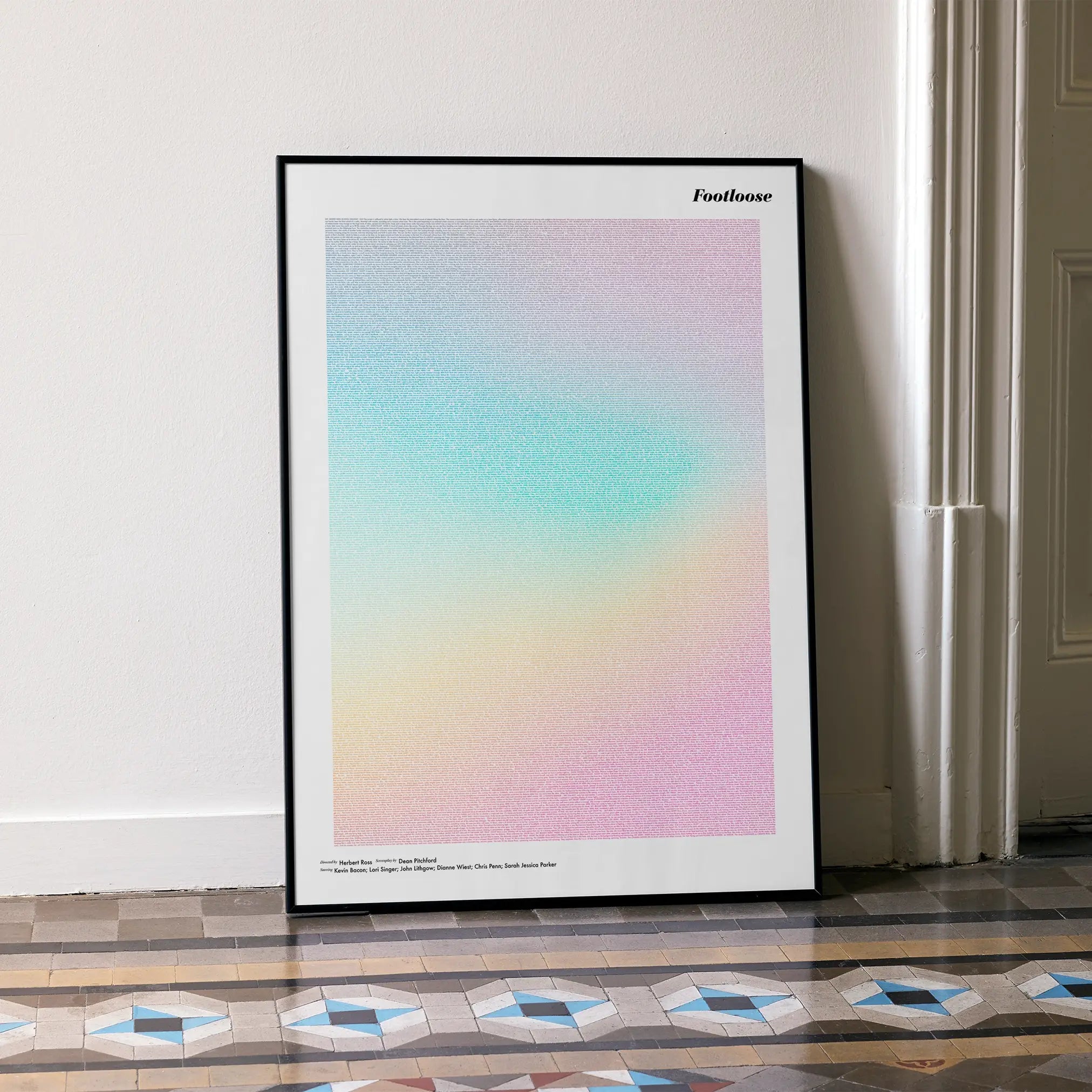 A framed Footloose movie script poster leaning against a wall in a minimalist interior.