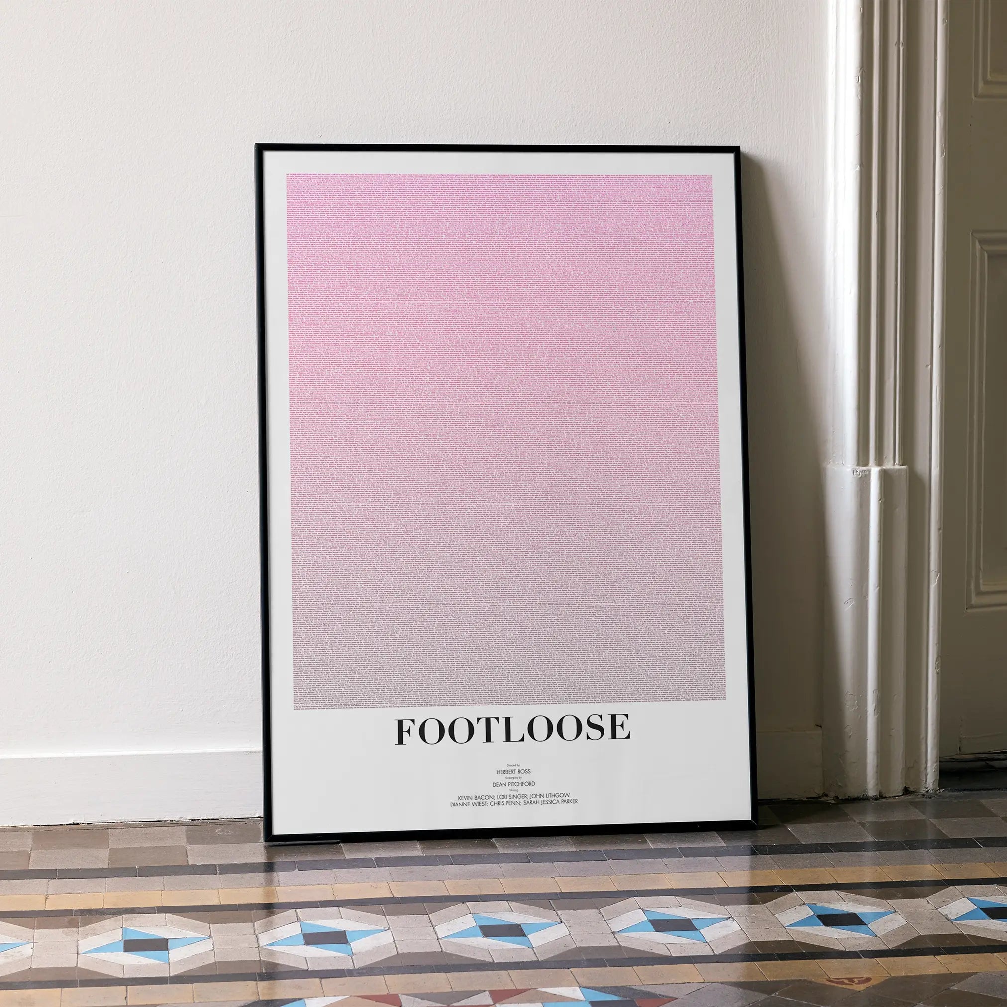 A framed Footloose movie script poster leaning against a wall in a minimalist interior.