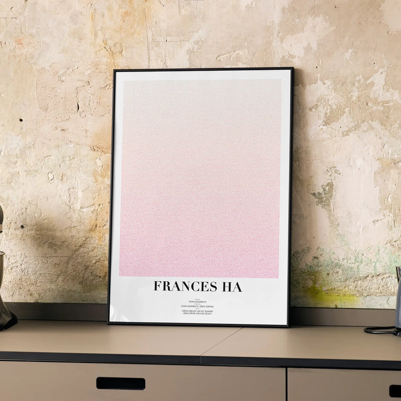 A framed Frances Ha movie script poster displayed on a cabinet in a minimalist interior.