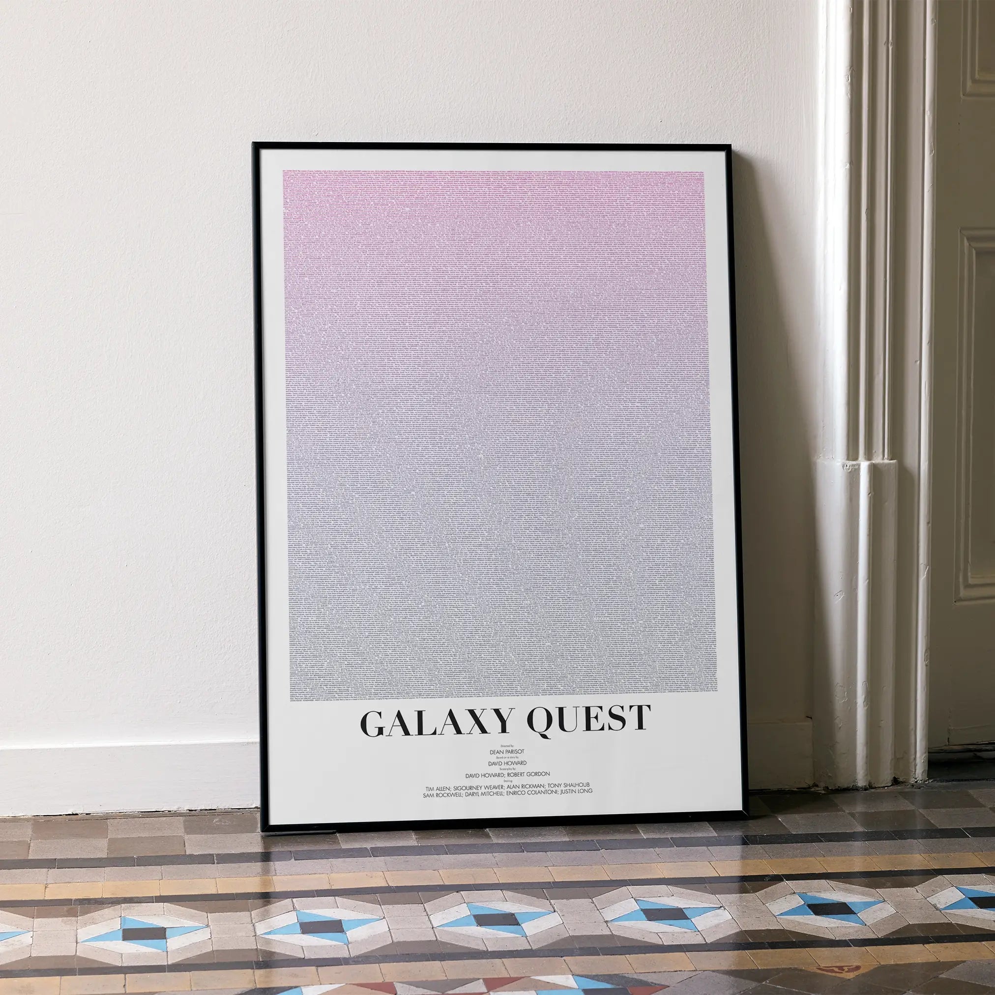 A framed Galaxy Quest movie script poster leaning against a wall in a minimalist interior.