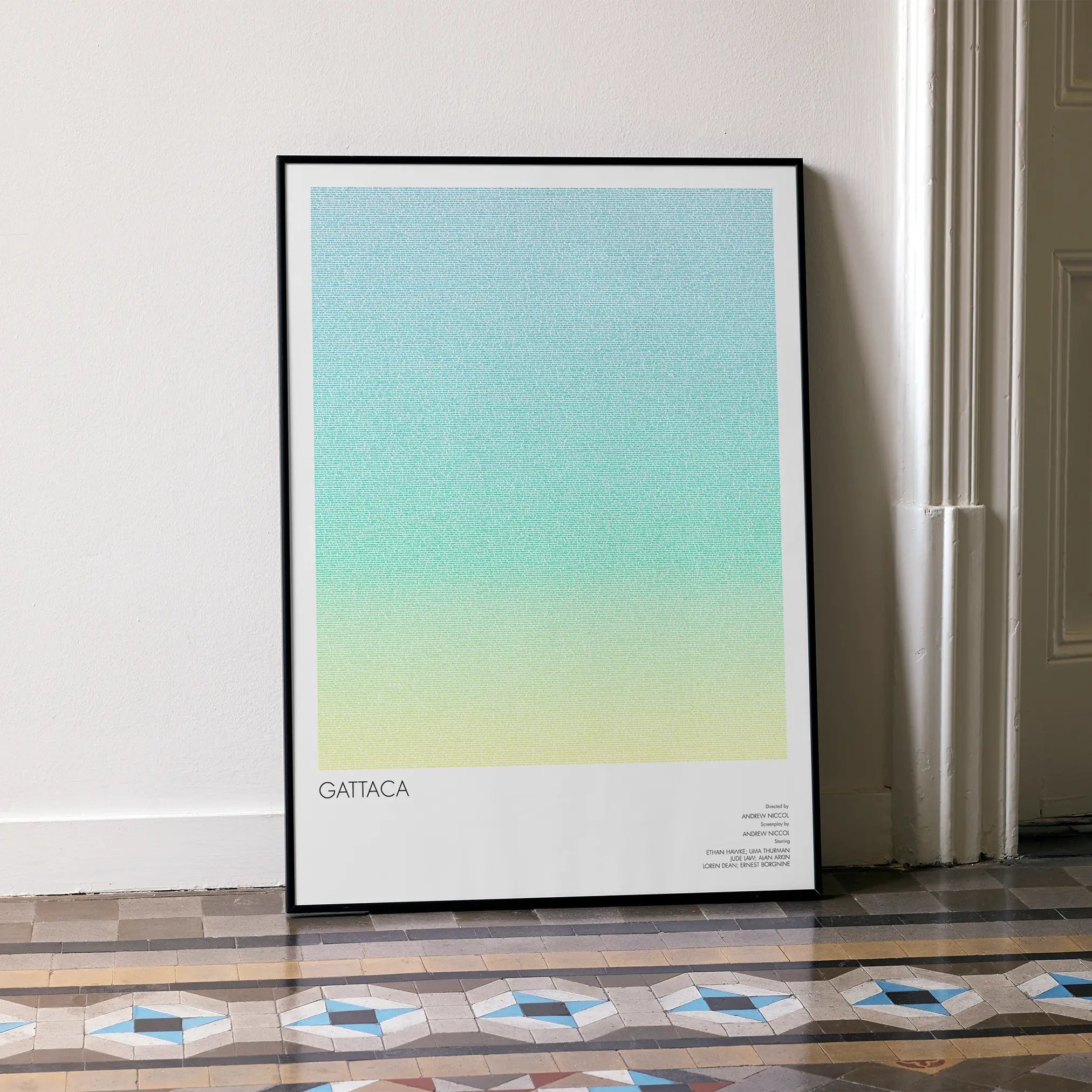A framed Gattaca movie script poster leaning against a wall in a minimalist interior.
