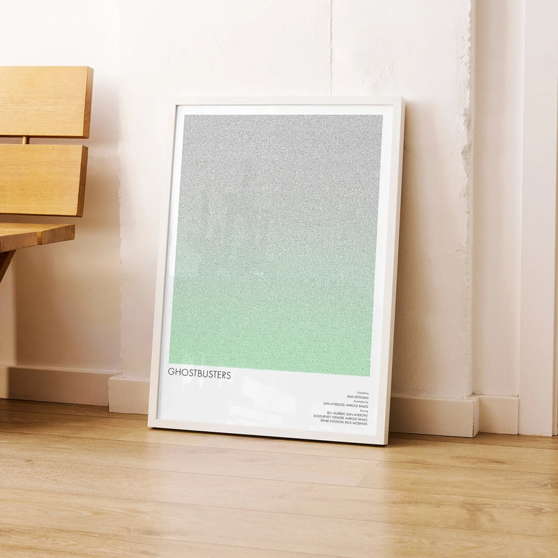 A framed Ghostbusters movie script poster leaning against a wall in a modern interior.