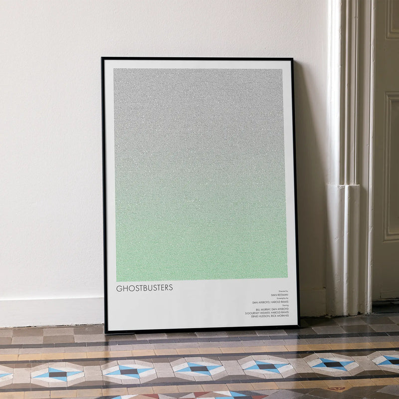 A framed Ghostbusters movie script poster leaning against a wall in a minimalist interior.