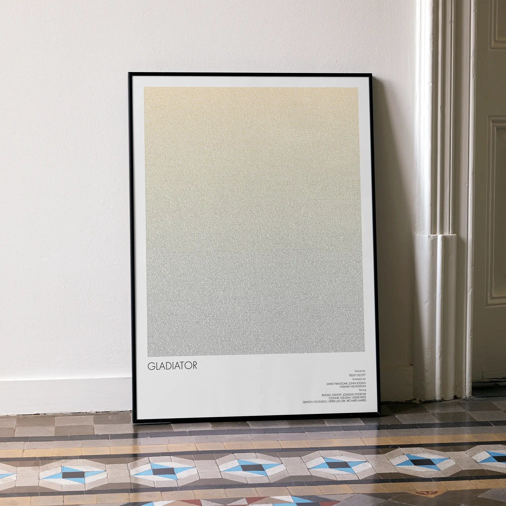 A framed Gladiator movie script poster leaning against a wall in a minimalist interior.