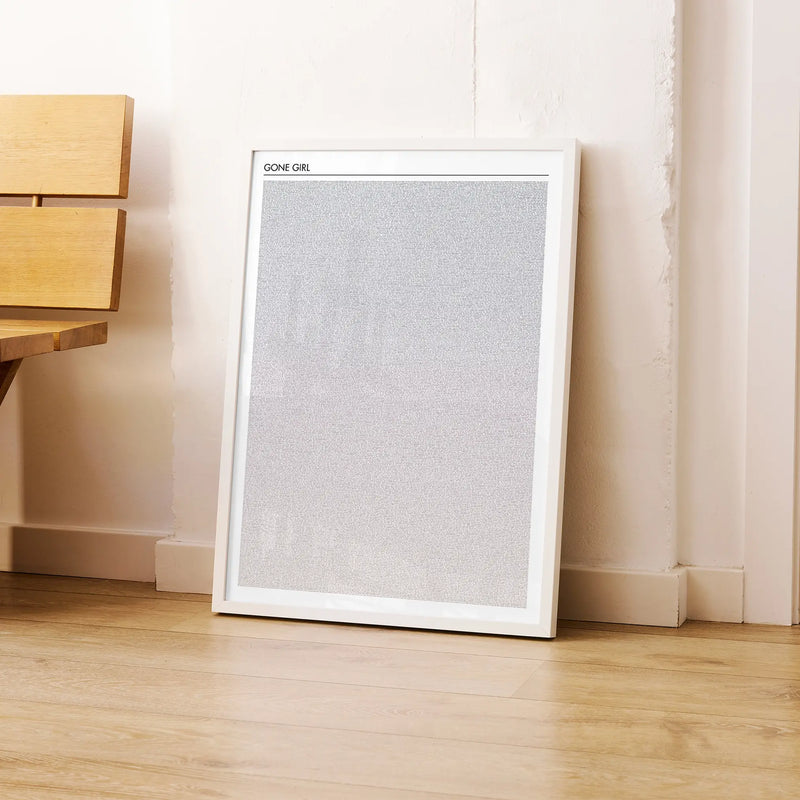 A framed Gone Girl movie script poster leaning against a wall in a modern interior.
