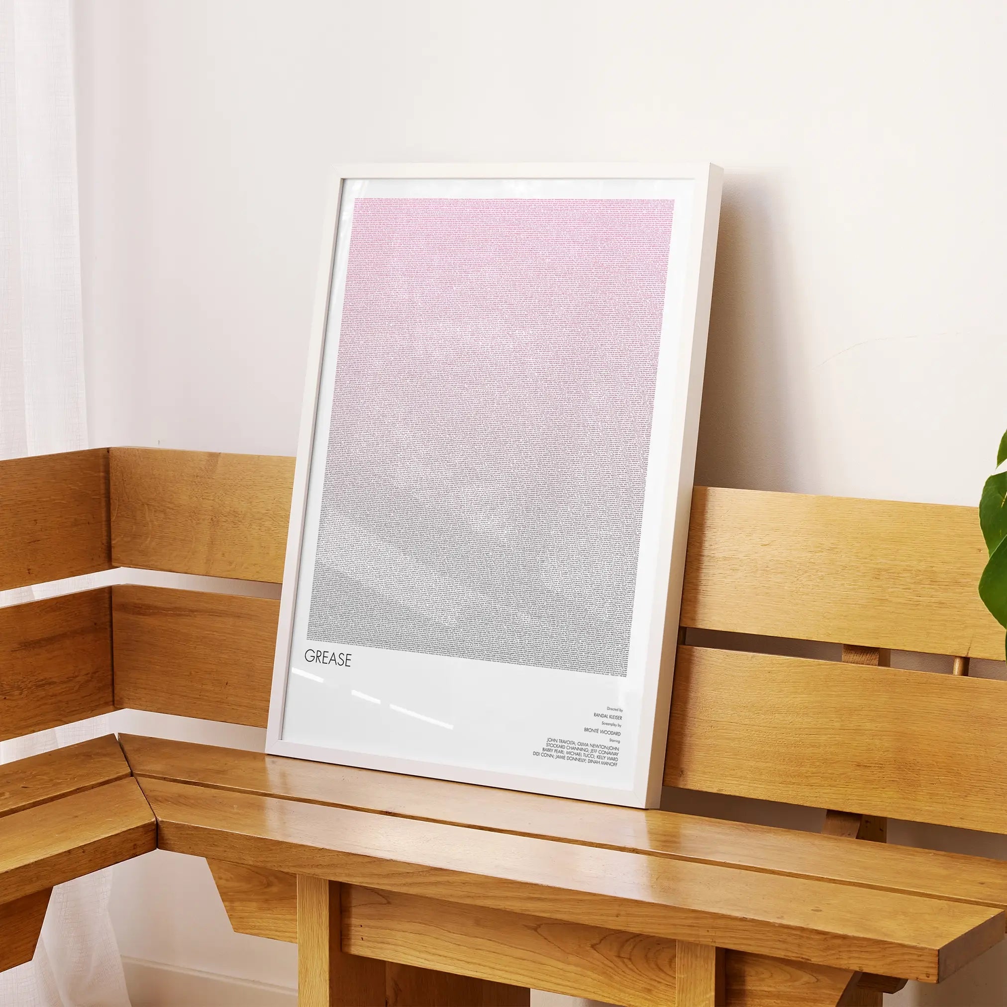 A framed Grease movie script poster displayed on a sideboard in a contemporary space.