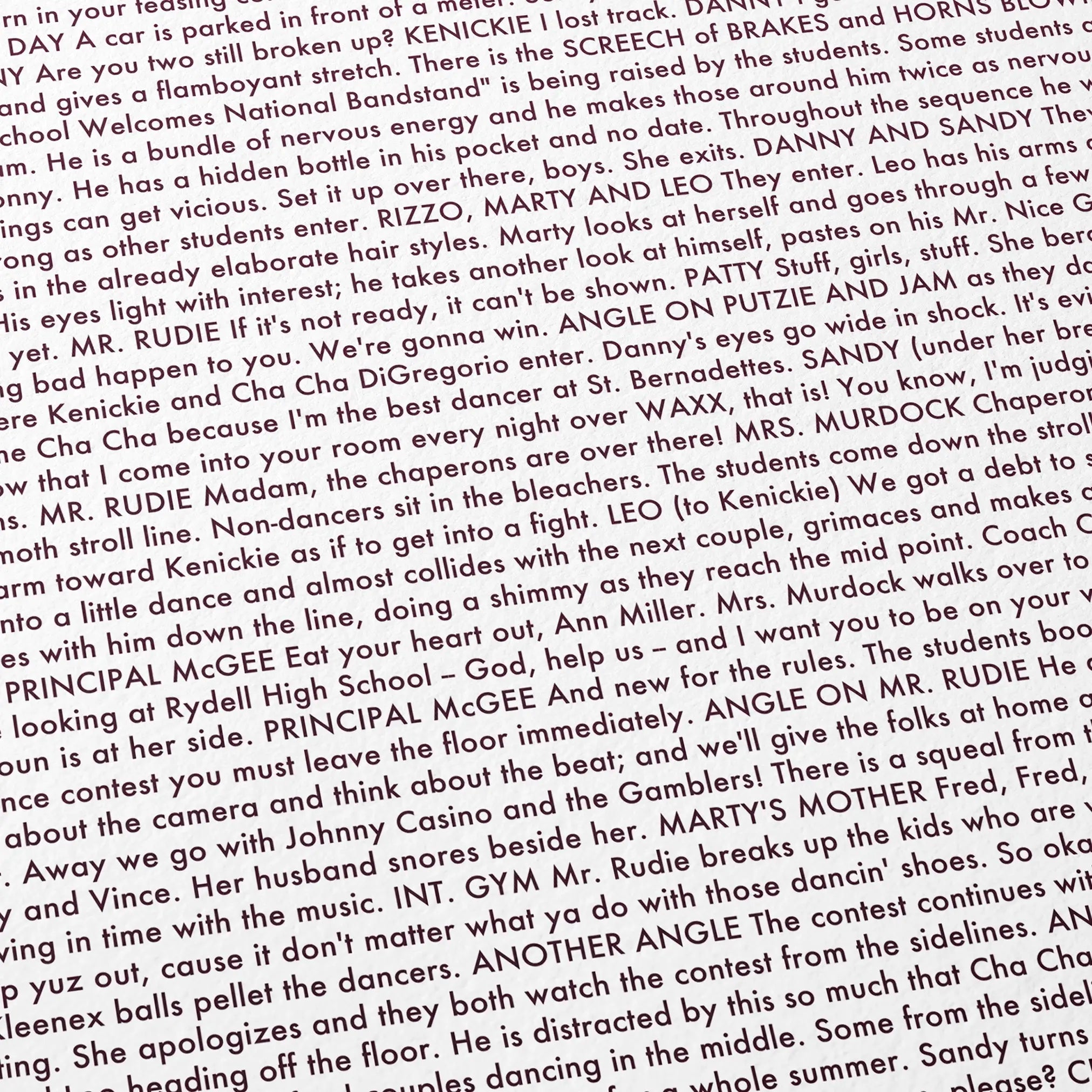 Close-up detail of the Grease movie script poster showing dense typographic text.