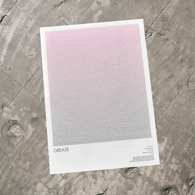 A Grease movie script poster laid flat on a textured floor surface.