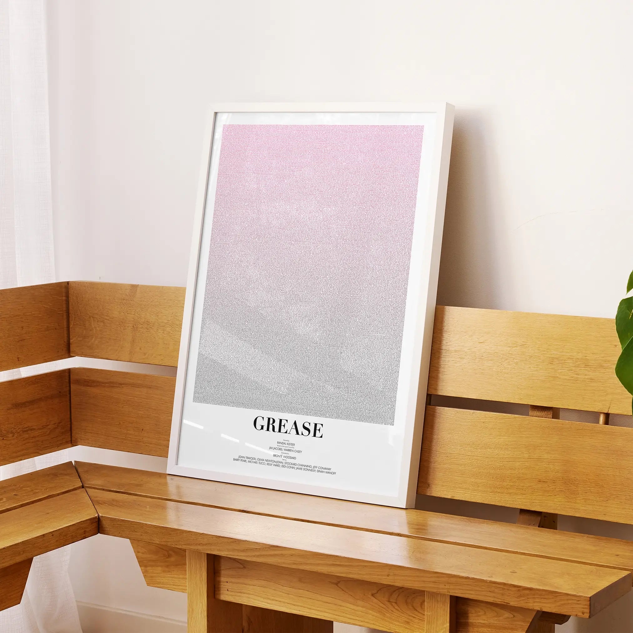 A framed Grease movie script poster displayed on a sideboard in a contemporary space.