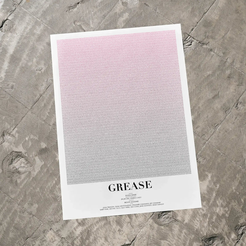 A Grease movie script poster laid flat on a textured floor surface.