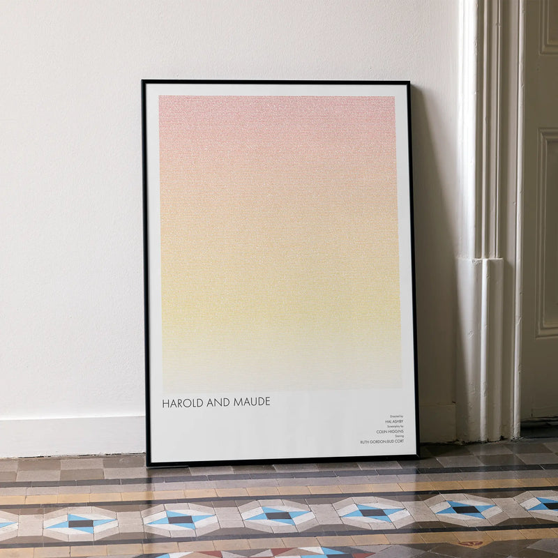 A framed Harold and Maude movie script poster leaning against a wall in a minimalist interior.